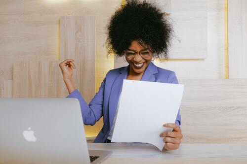 A woman smiling at his computer | Bill collector Michigan