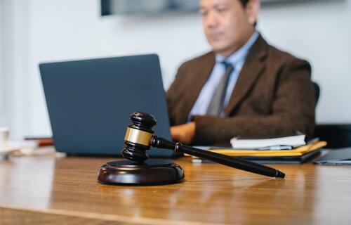 A man on a computer next to a legal scale | collection services Michigan.jpg