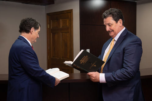 A photo of John Muller and Mike Muller, commercial collections experts based in Michigan, looking through law books.
