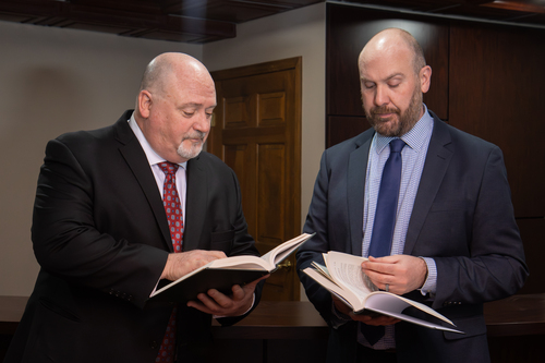 A photo of two Michigan debt collector attorneys reading law books.