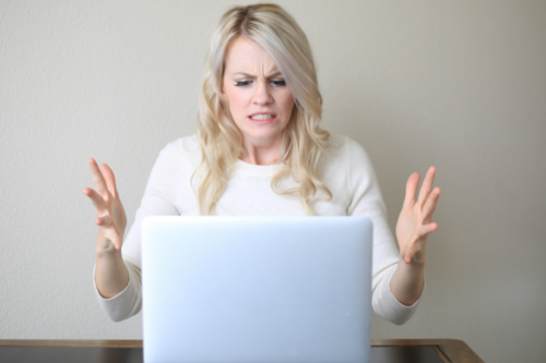 A photo of a woman looking very frustrated at her laptop screen, representing a creditor frustrated with a difficult debtor personality. The Mullers' Michigan collection services can help with this.