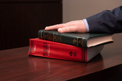 A photo of a lawyer's hand resting on two law books.