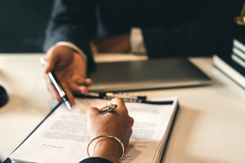 Photo of a contract on a lawyer's desk being discussed by two people.