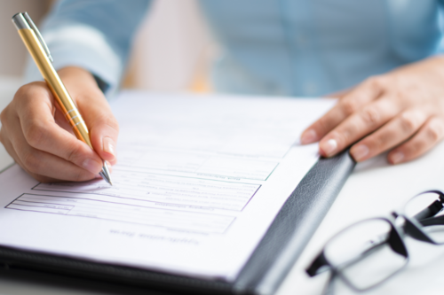 Photo of a man sitting at a desk and holding a pencil while looking at a financial document.