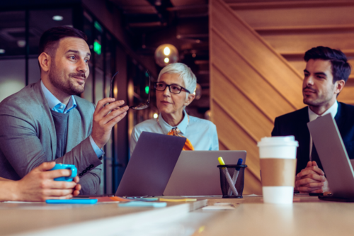 Photo of three business people talking at a conference table.